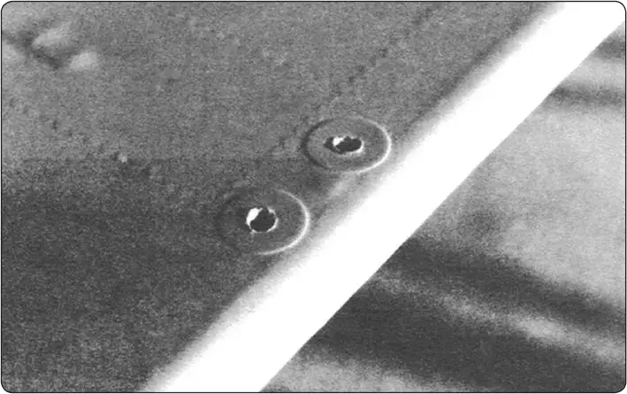Drain grommets cemented to the underside of an aircraft control surface