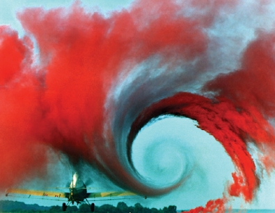 Crop-dusting aircraft producing visible wingtip vortices as air circulates around the wingtips during flight