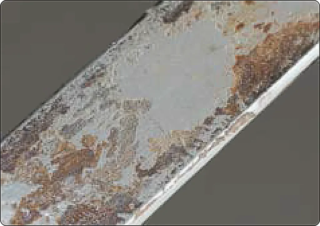 Close-up of fretting corrosion at a metal contact surface, showing localized wear and oxidation caused by repeated small movements between contacting components