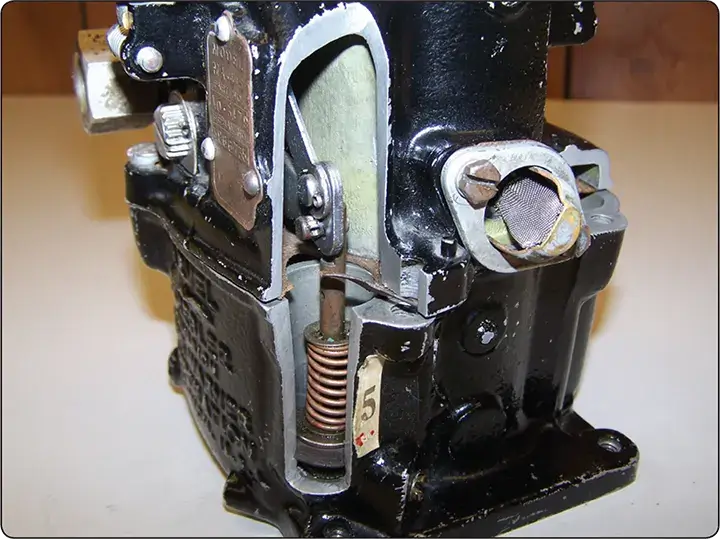 Cutaway view of a carburetor accelerating pump showing its internal components and fuel delivery mechanism