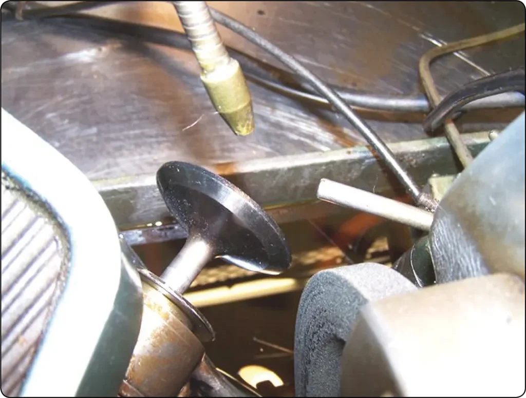 Engine valve clamped in a grinding machine chuck and positioned for grinding the valve face to the specified angle and finish