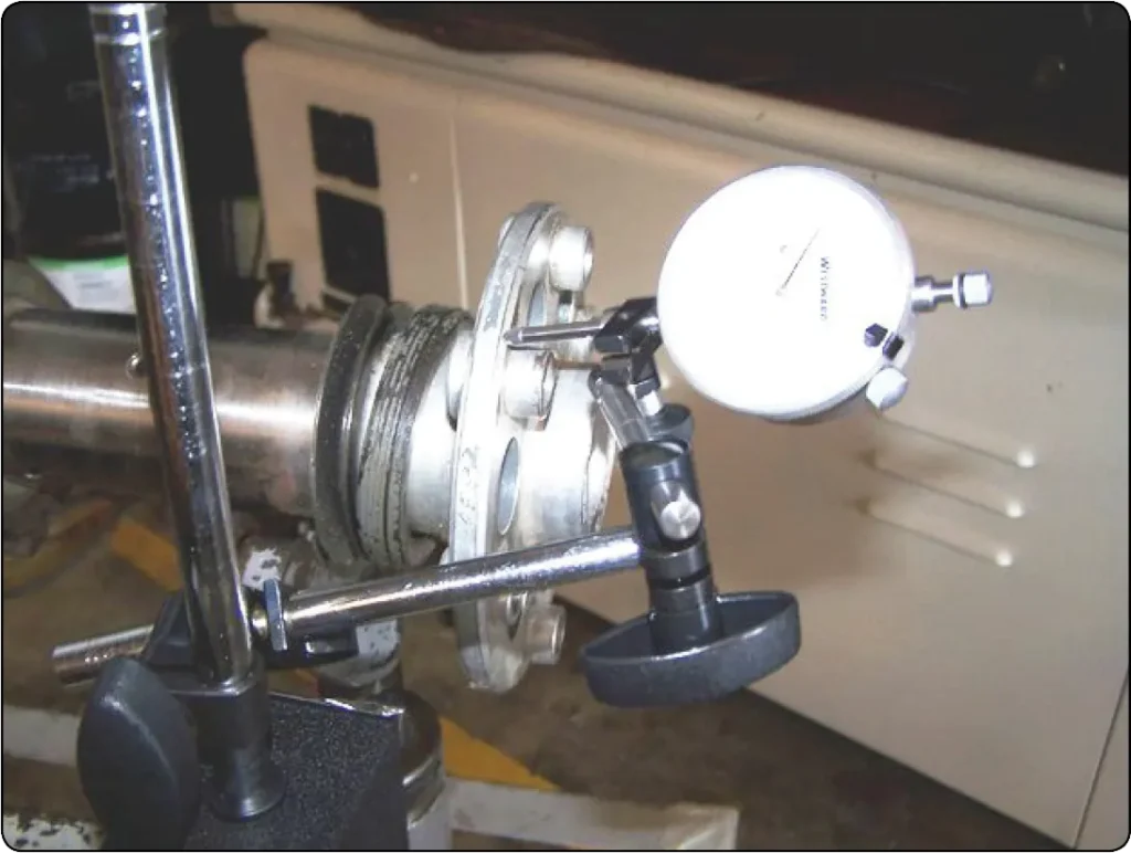 Illustration showing a dial indicator positioned against an aircraft engine crankshaft to measure runout and check for bending or dimensional deviation