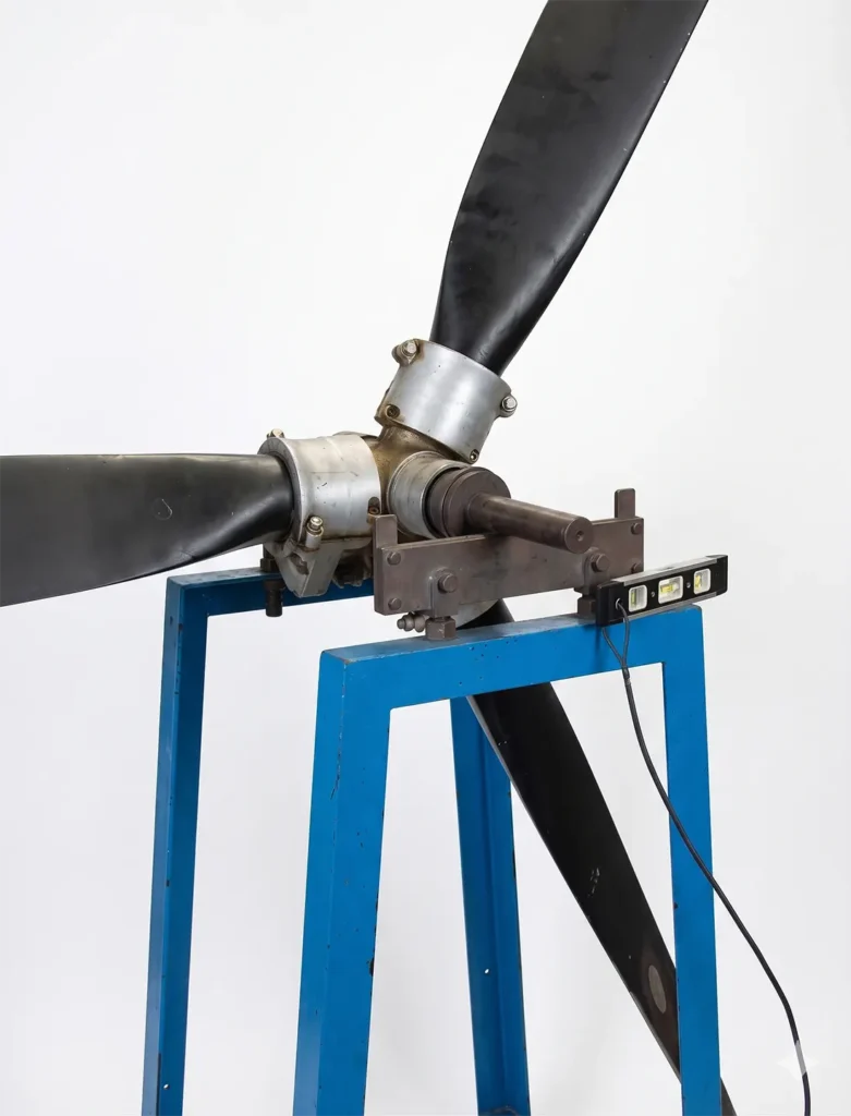 Illustration of a static propeller balancing setup showing an aircraft propeller mounted on a balancing fixture to detect uneven weight distribution